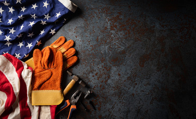 Happy Labor day concept. American flag with different construction tools on dark stone background, with copy space for text.