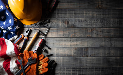 Happy Labor day concept. American flag with different construction tools on dark wooden background, with copy space for text.