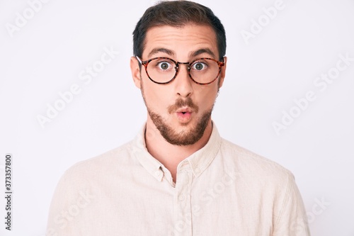Young handsome man wearing casual clothes and glasses scared and amazed with open mouth for surprise, disbelief face © Krakenimages.com