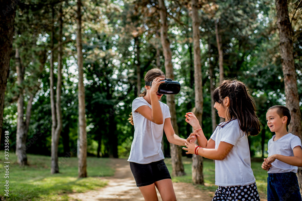 School children in white t shirts having fun with virtual reality headset outdoor in the park School children in white t shirts having fun with virtual reality headset outdoor in the park