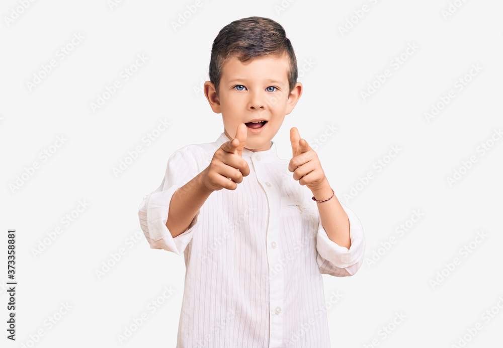Cute blond kid wearing elegant shirt pointing fingers to camera with happy and funny face. good energy and vibes. Cute blond kid wearing elegant shirt pointing fingers to camera with happy and funny face. good energy and vibes.