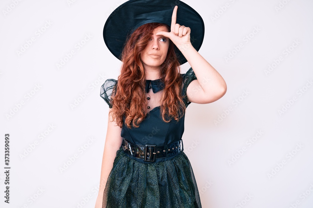 Young beautiful woman wearing witch halloween costume making fun of people with fingers on forehead doing loser gesture mocking and insulting. Young beautiful woman wearing witch halloween costume making fun of people with fingers on forehead doing loser gesture mocking and insulting.