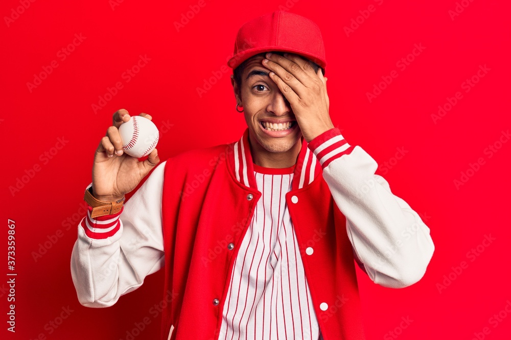Young african amercian man wearing baseball uniform holding ball stressed and frustrated with hand on head, surprised and angry face Young african amercian man wearing baseball uniform holding ball stressed and frustrated with hand on head, surprised and angry face