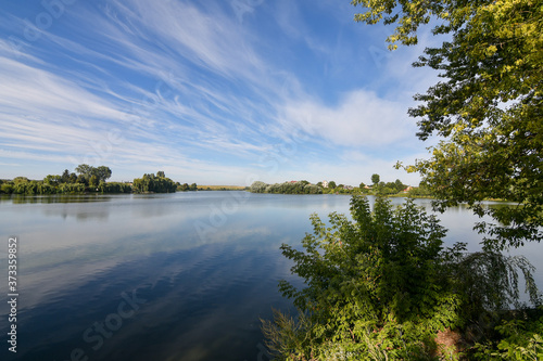 Beautiful summer landscape with lake and serene blue sky reflected in the water surface. Calm morning scenery