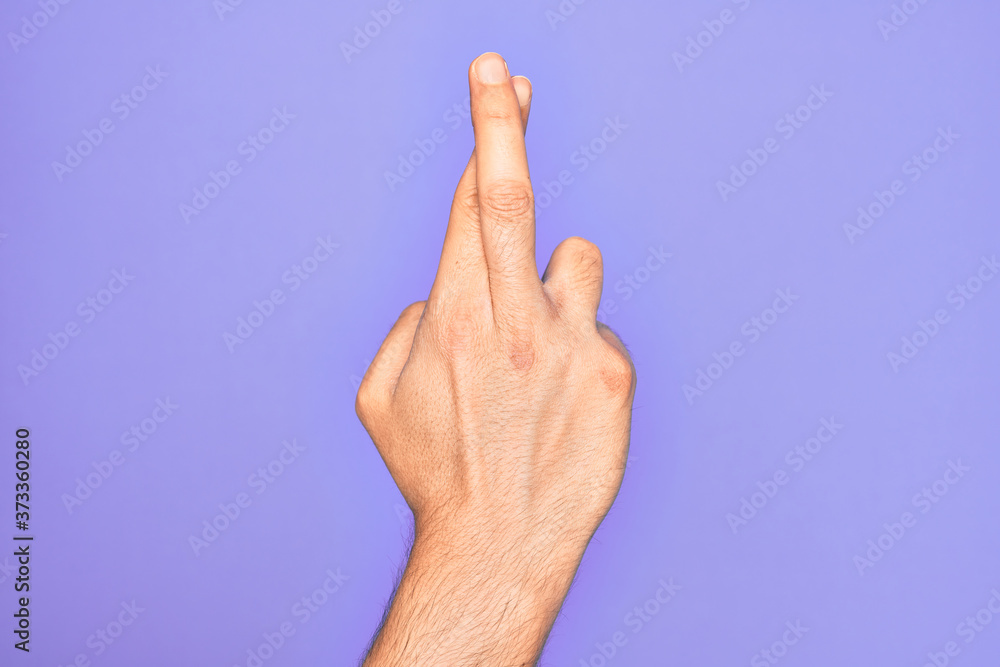 Hand of caucasian young man showing fingers over isolated purple background gesturing fingers crossed, superstition and lucky gesture, lucky and hope expression