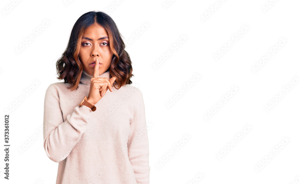 Young beautiful mixed race woman wearing winter turtleneck sweater asking to be quiet with finger on lips. silence and secret concept. Young beautiful mixed race woman wearing winter turtleneck sweater asking to be quiet with finger on lips. silence and secret concept.