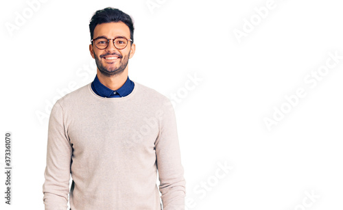 Young handsome hispanic man wearing elegant clothes and glasses with a happy and cool smile on face. lucky person. © Krakenimages.com