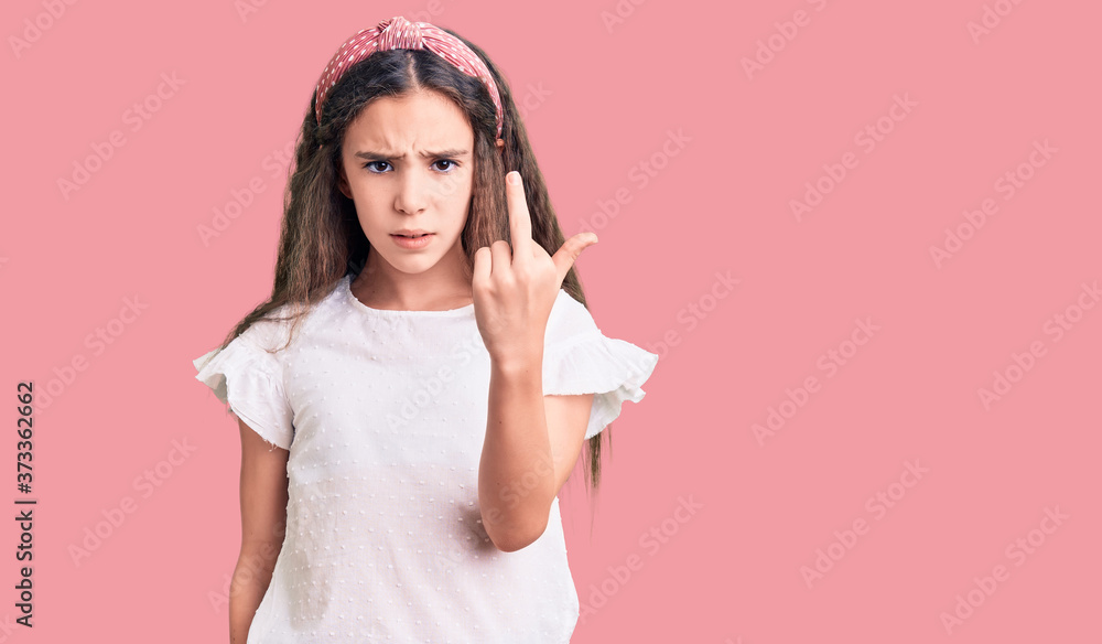 Cute hispanic child girl wearing casual white tshirt showing middle finger, impolite and rude fuck off expression Cute hispanic child girl wearing casual white tshirt showing middle finger, impolite and rude fuck off expression