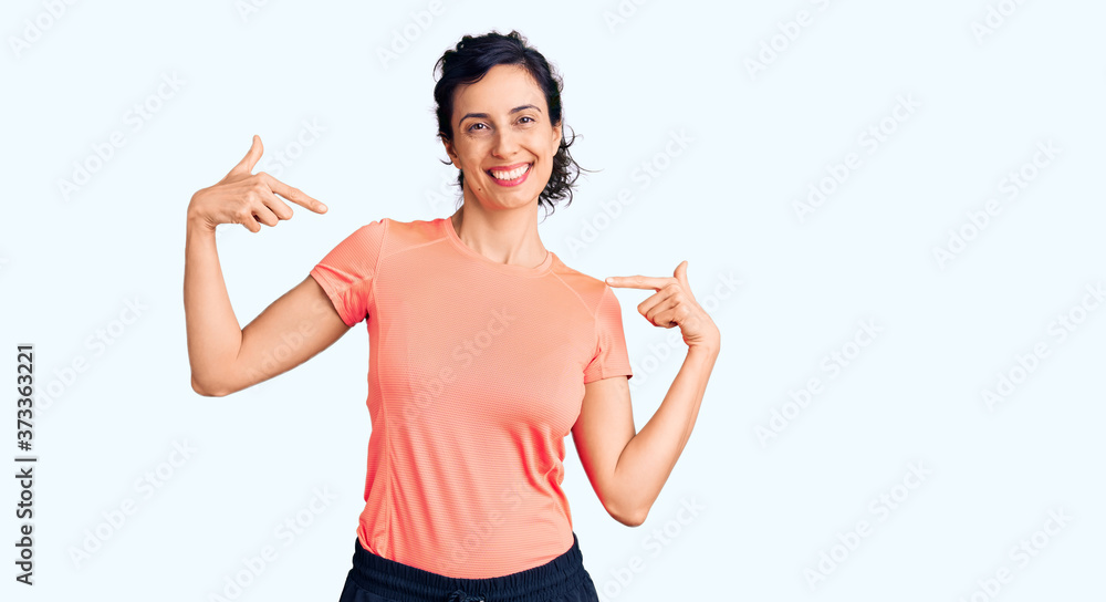 Young beautiful hispanic woman wearing sportswear looking confident with smile on face, pointing oneself with fingers proud and happy. Young beautiful hispanic woman wearing sportswear looking confident with smile on face, pointing oneself with fingers proud and happy.