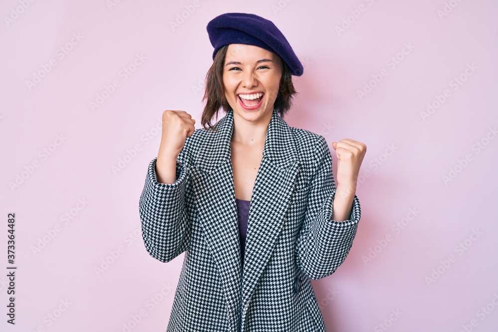 Young beautiful woman wearing french look with beret screaming proud, celebrating victory and success very excited with raised arms Young beautiful woman wearing french look with beret screaming proud, celebrating victory and success very excited with raised arms