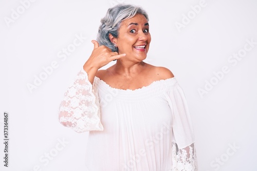 Senior hispanic grey- haired woman wearing casual clothes smiling doing phone gesture with hand and fingers like talking on the telephone. communicating concepts.