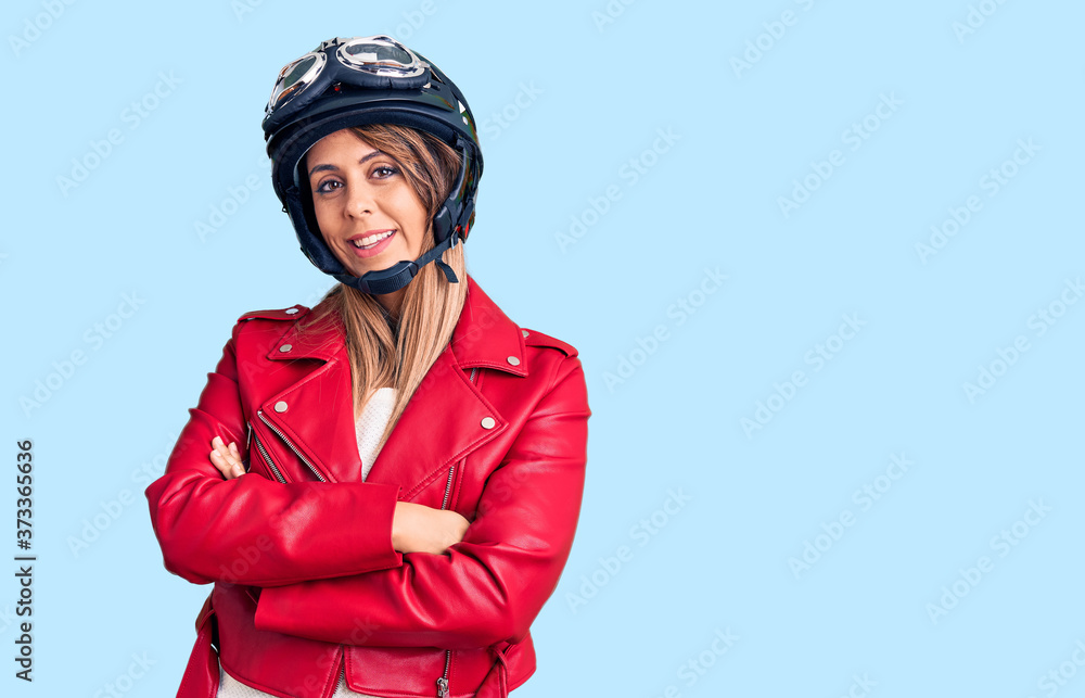 Young beautiful woman wearing motorcycle helmet happy face smiling with crossed arms looking at the camera. positive person. Young beautiful woman wearing motorcycle helmet happy face smiling with crossed arms looking at the camera. positive person.