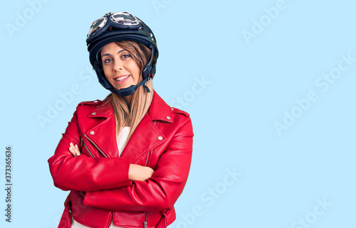 Young beautiful woman wearing motorcycle helmet happy face smiling with crossed arms looking at the camera. positive person. © Krakenimages.com