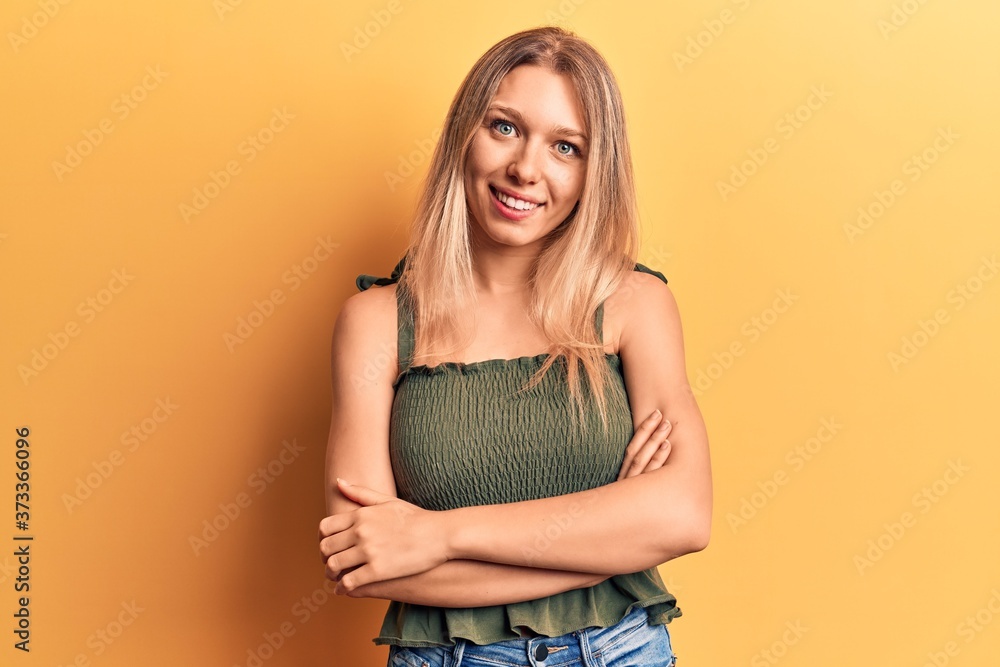 Young blonde woman wearing casual clothes happy face smiling with crossed arms looking at the camera. positive person. Young blonde woman wearing casual clothes happy face smiling with crossed arms looking at the camera. positive person.