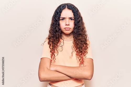 Beautiful kid girl with curly hair wearing casual clothes skeptic and nervous, disapproving expression on face with crossed arms. negative person.