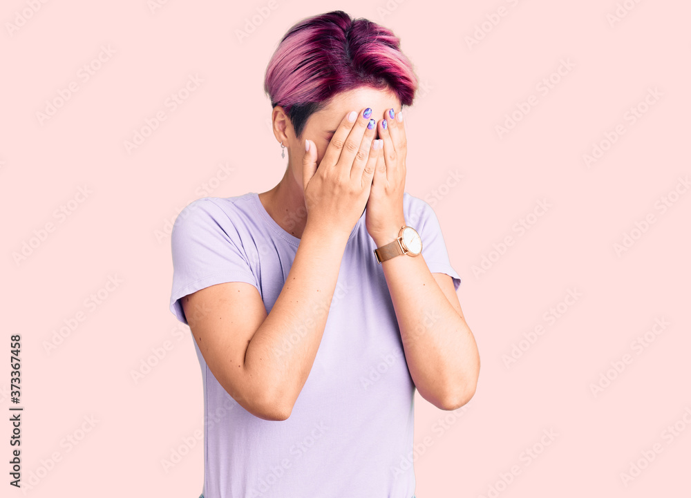 Young beautiful woman with pink hair wearing casual clothes with sad expression covering face with hands while crying. depression concept.