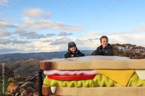 Boys posing with giant sandwich on hillside with wide sweeping view in background photo