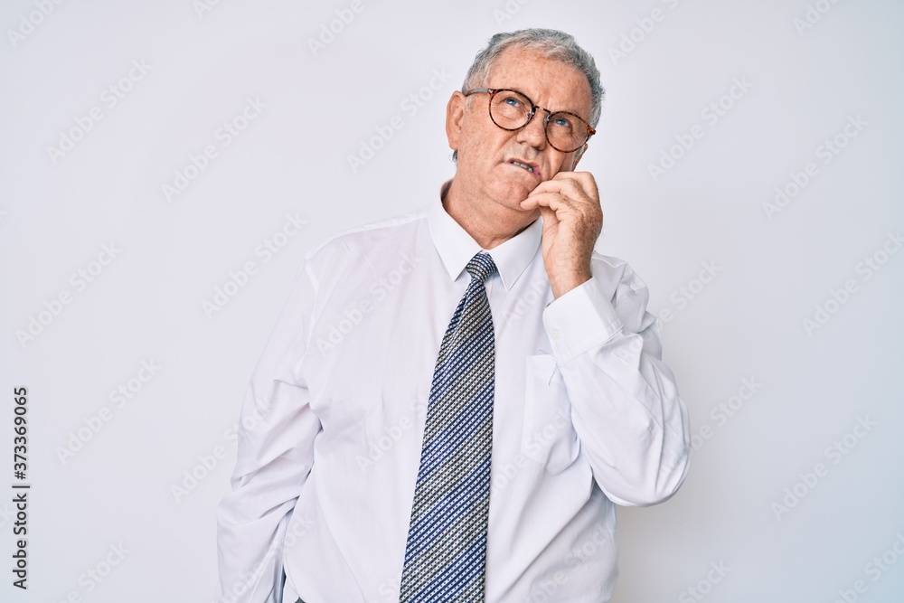Senior grey-haired man wearing business clothes serious face thinking about question with hand on chin, thoughtful about confusing idea Senior grey-haired man wearing business clothes serious face thinking about question with hand on chin, thoughtful about confusing idea