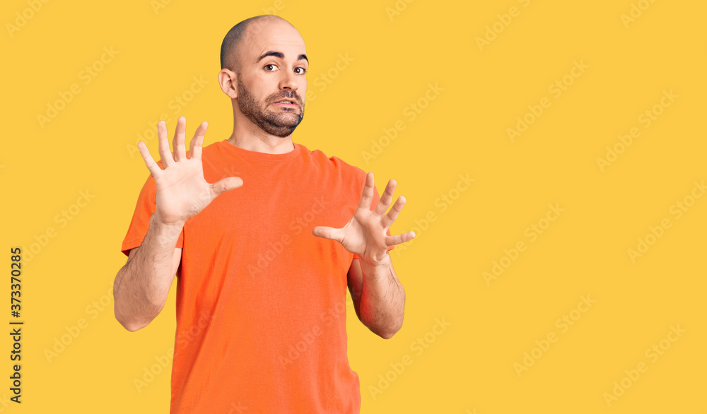 Young handsome man wering casual t shirt afraid and terrified with fear expression stop gesture with hands, shouting in shock. panic concept.