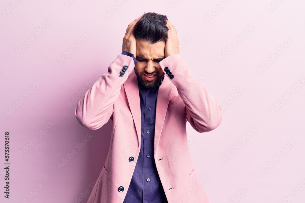 Young handsome man with beard wearing elegant jacket suffering from headache desperate and stressed because pain and migraine. hands on head.