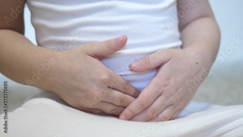A small child experiences abdominal pain. Kid holds his hands on his stomach. Digestive tract poisoning. Appendicitis.