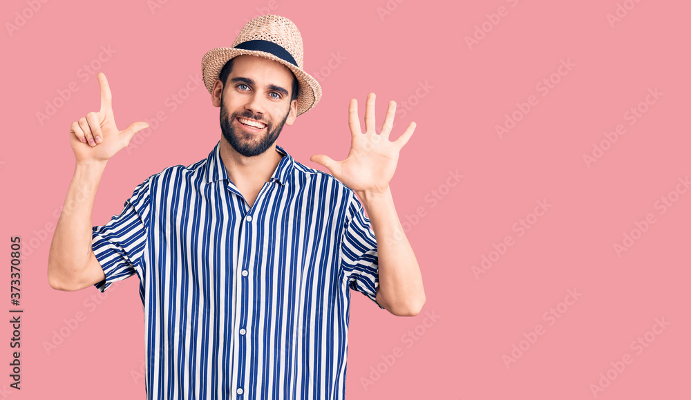 Young handsome man with beard wearing summer hat and striped shirt showing and pointing up with fingers number seven while smiling confident and happy. Young handsome man with beard wearing summer hat and striped shirt showing and pointing up with fingers number seven while smiling confident and happy.