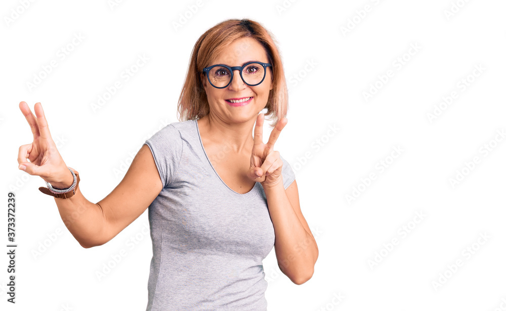 Young blonde woman wearing casual clothes smiling looking to the camera showing fingers doing victory sign. number two. Young blonde woman wearing casual clothes smiling looking to the camera showing fingers doing victory sign. number two.