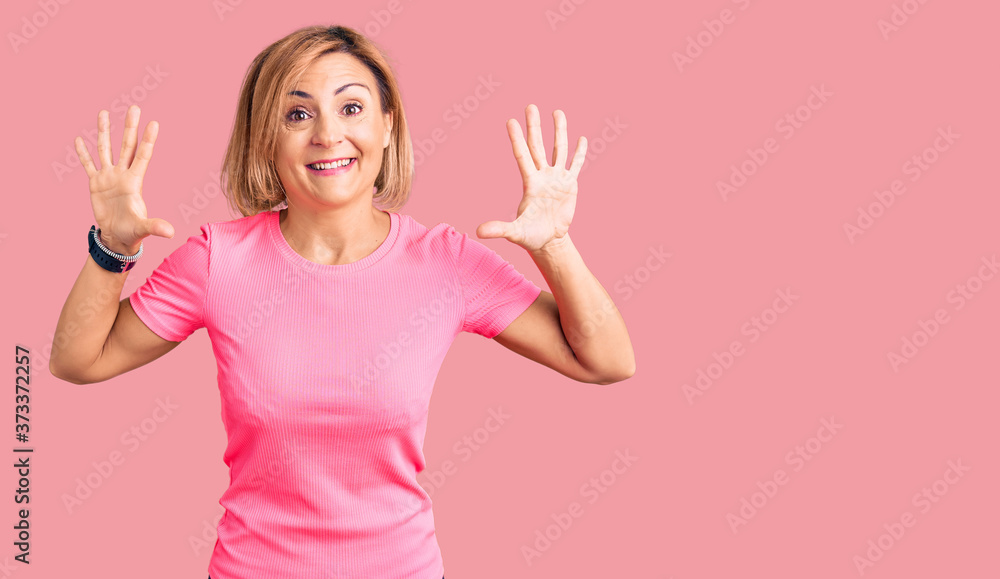 Young blonde woman wearing sportswear showing and pointing up with fingers number ten while smiling confident and happy. Young blonde woman wearing sportswear showing and pointing up with fingers number ten while smiling confident and happy.