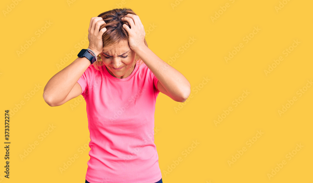 Young blonde woman wearing sportswear suffering from headache desperate and stressed because pain and migraine. hands on head. Young blonde woman wearing sportswear suffering from headache desperate and stressed because pain and migraine. hands on head.