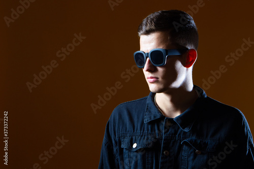 Man sunglasses. Young guy Portrait of a guy in a dark shirt. Man sunglasses on a brown background. Concept - sale of sunglasses. Fashion. Man in casual style. Fashion guy looking away.