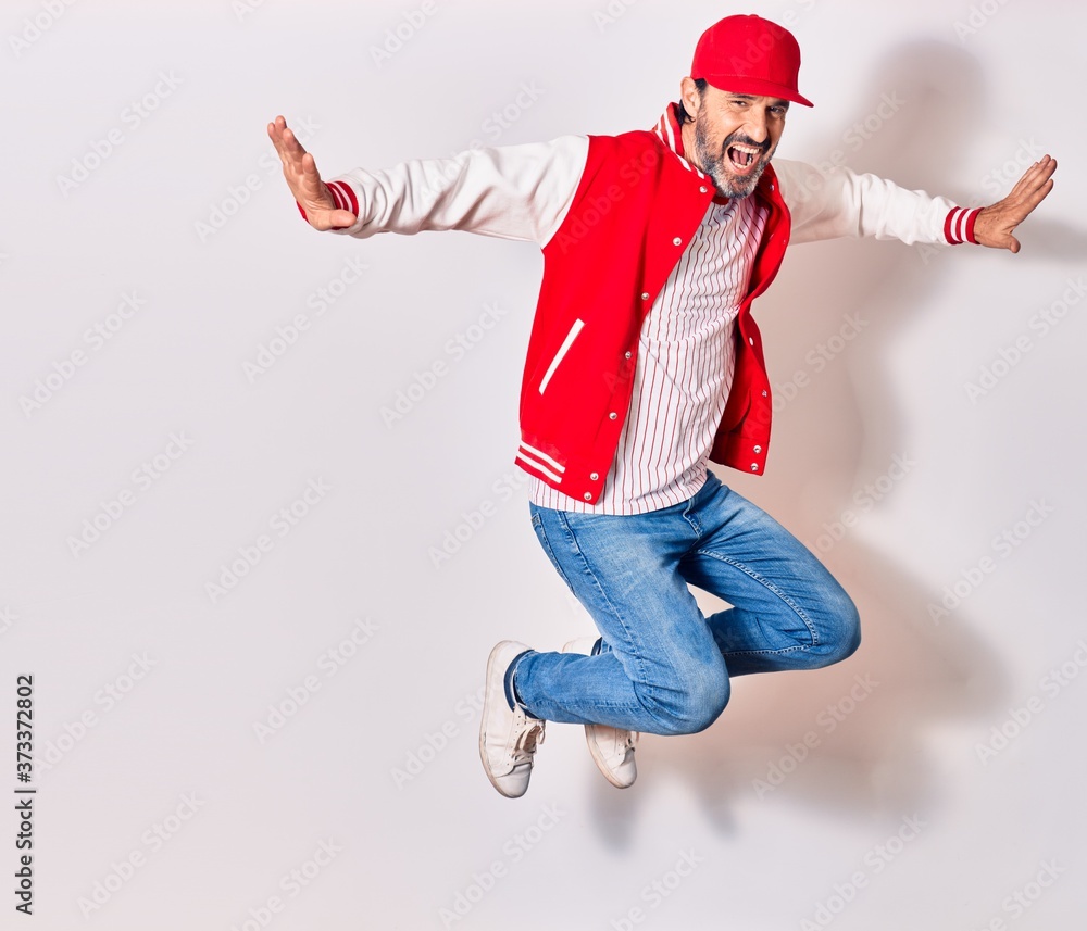 Middle age handsome man wearing baseball uniform smiling happy. Jumping with arms open over isolated white background