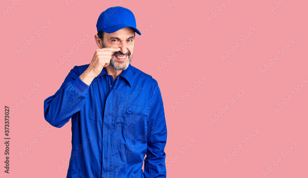 Middle age handsome man wearing mechanic uniform pointing with hand finger to face and nose, smiling cheerful. beauty concept Middle age handsome man wearing mechanic uniform pointing with hand finger to face and nose, smiling cheerful. beauty concept
