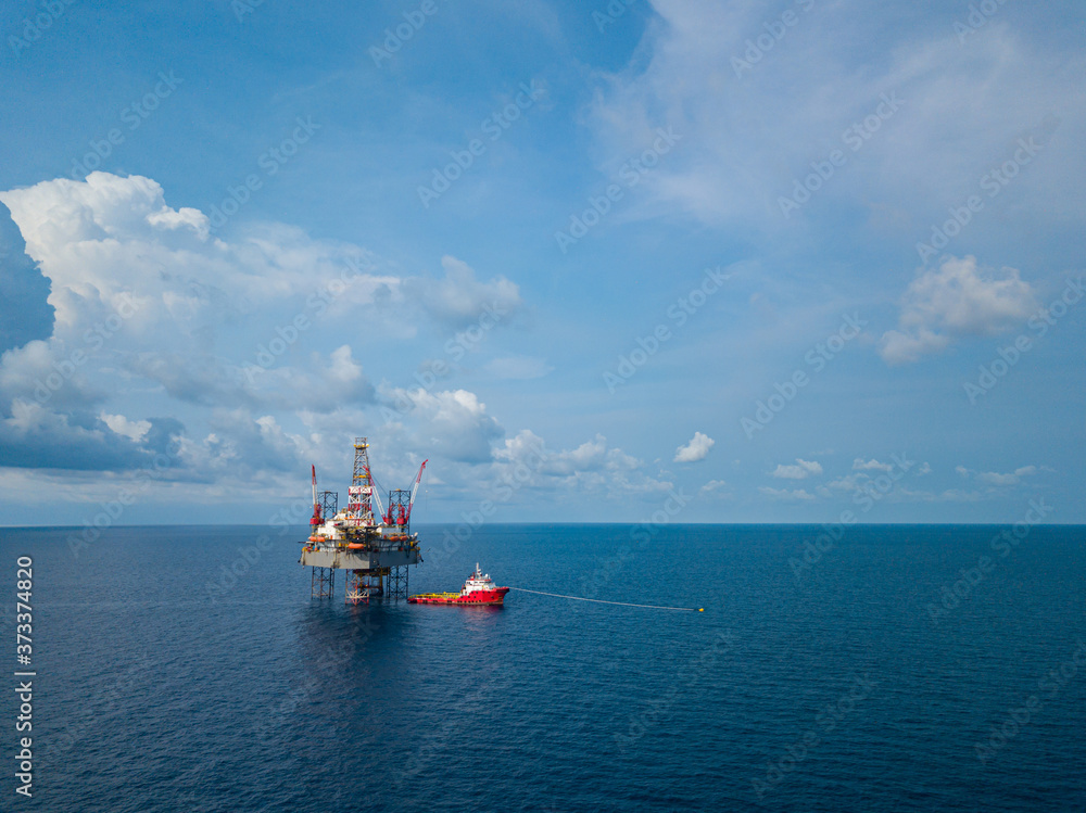 Aerial view from a drone of an offshore jack up rig at the offshore location with a supply boat