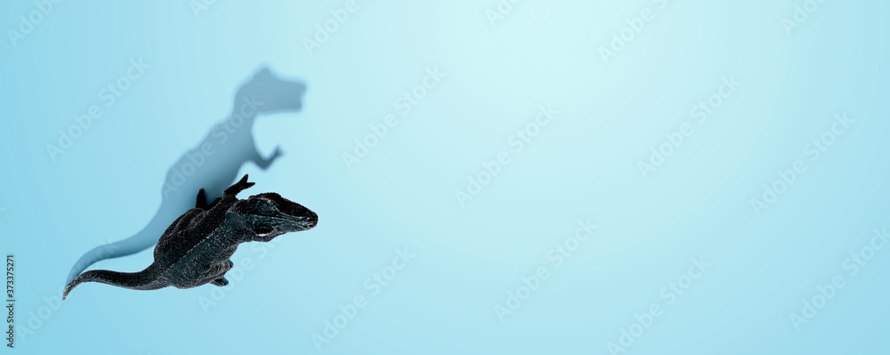 Fototapeta premium Tyrannosaurus toy with shadow from above - flat lay
