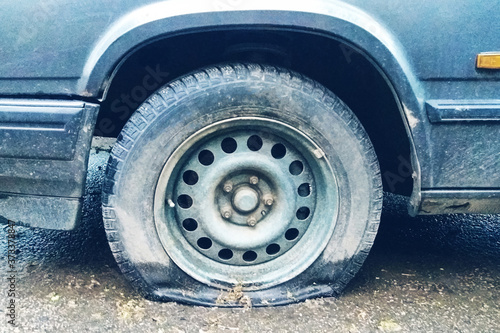 flat tyre of old car outdoors, dirty collapsed tyre close up