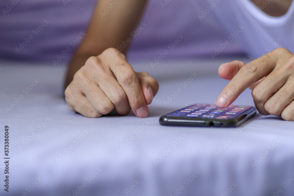 Man using a black smartphone on purple bed