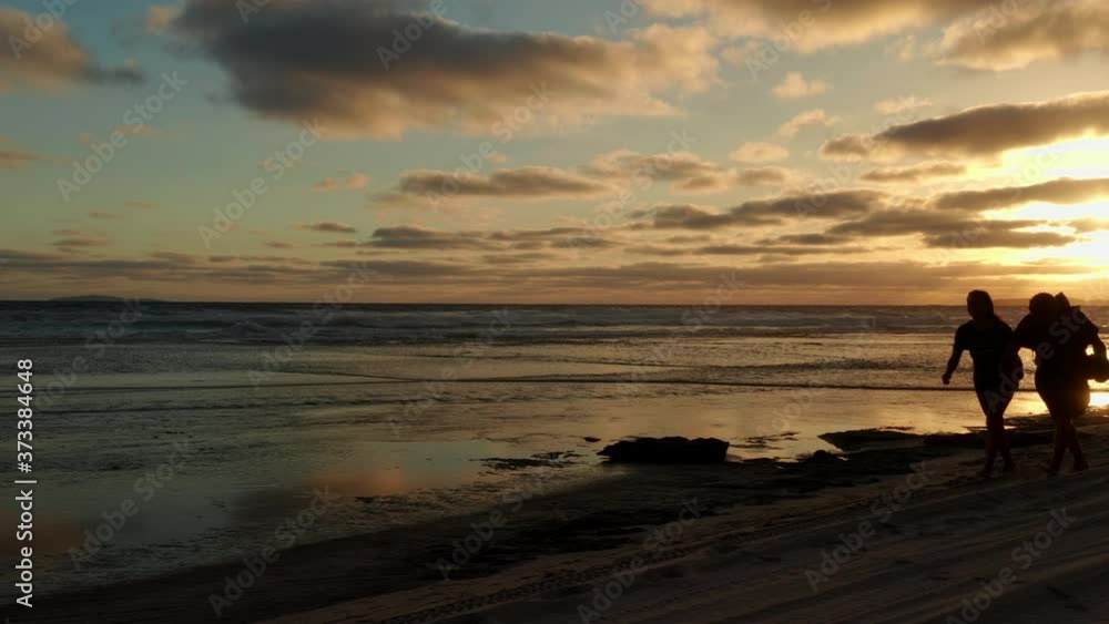 Couple walking on the Ninety Mile Beach, during sunset, in Victoria, Australia - Handheld view