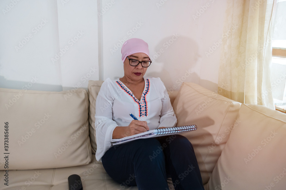 Portrait of an adult woman filling out a patient form at the doctor's office during her recovery from cancer