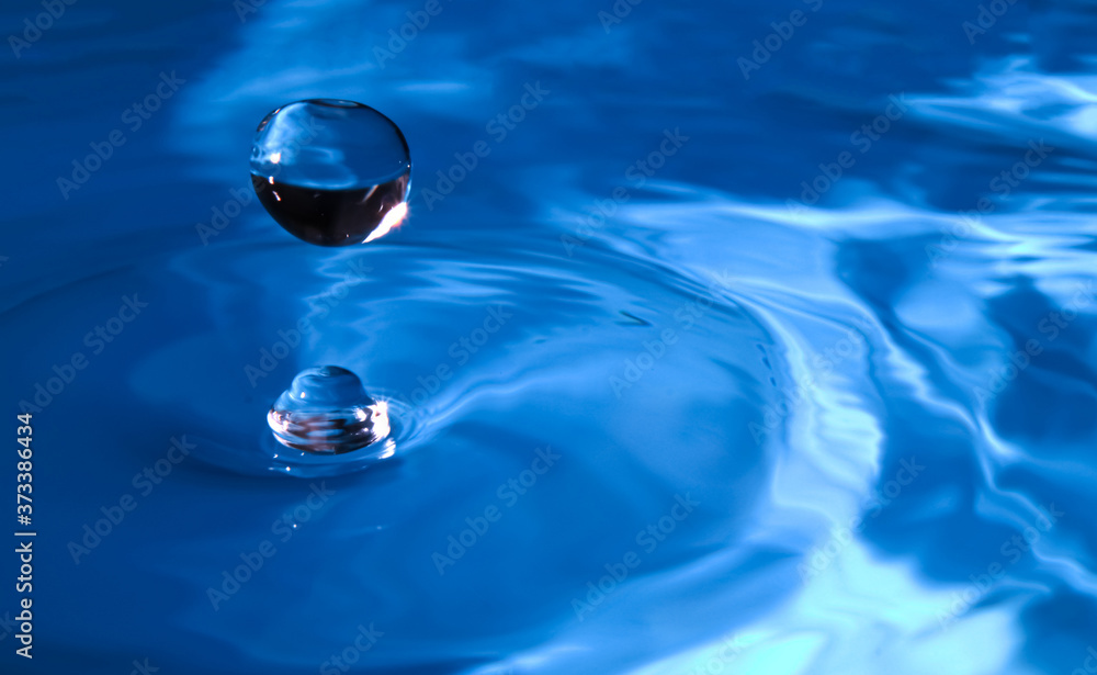 Water droplets fall down closely into the dark blue water, making it the perfect center in nature. Selective focus Water droplets fall down closely into the dark blue water, making it the perfect center in nature. Selective focus
