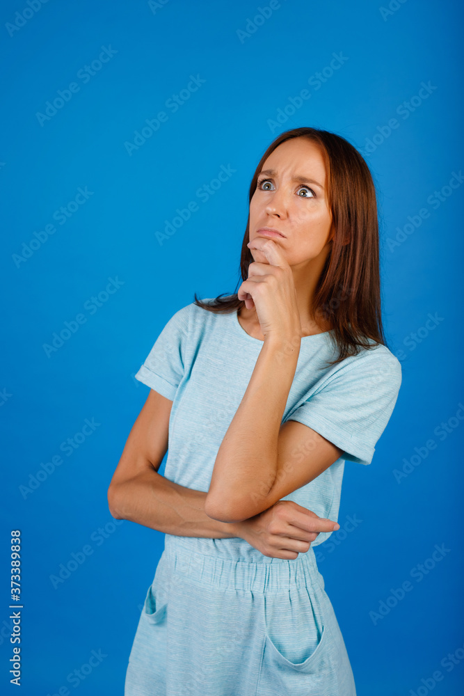 Image of thinking young lady standing isolated over blue background. Looking aside. Image of thinking young lady standing isolated over blue background. Looking aside.