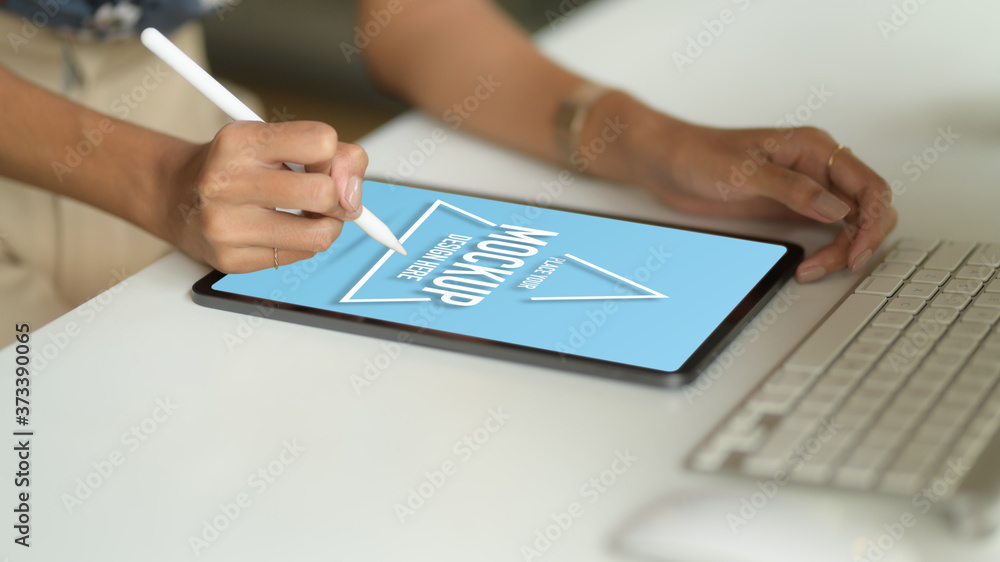 Female hand drawing on mock up tablet with stylus on computer table Female hand drawing on mock up tablet with stylus on computer table