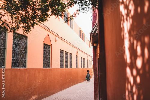 Canvas Print Woman in traditional arabic black cape and paranja carrying bag on her head on Marrakesh street