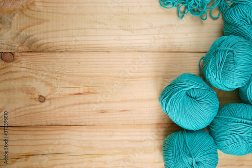 Balls of colored natural yarn in turquoise shades on a wooden background. Selective focus. Space for text. Copy space. Creativity and Hobbies