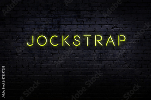 Foto Neon sign. Word jockstrap against brick wall. Night view