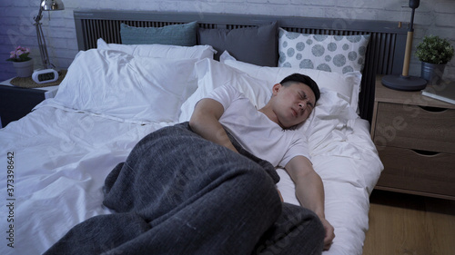 Quadro su tela asian male tossing and turning on bed is having a disturbed sleep