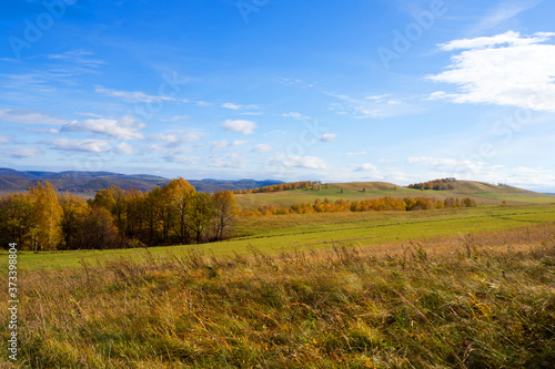 Landscape panorama of a hilly area with autumn colors and blue sky.