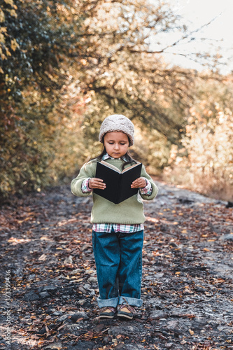 Little girl is reading a book on an autumn day. Education, school, development.