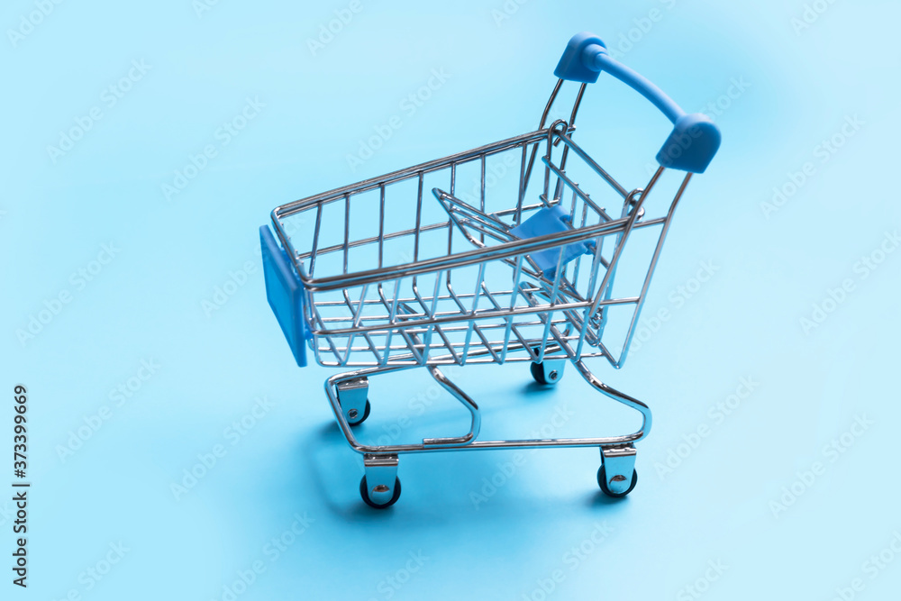 Close-up of shopping trolley on blue background with some copy space flat lay minimalism concept Close-up of shopping trolley on blue background with some copy space flat lay minimalism concept