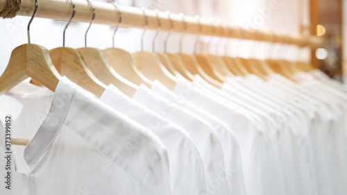 Fotografie Female clothes shirts white on rail hanging on hangers.