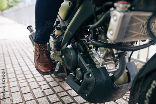 Close-up image of motorcyclist in leather shoes pushing pedal to start riding
